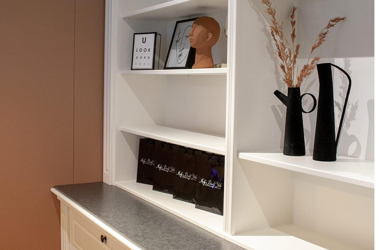 Witte wandkast met decoratie en Marly's Beauty Studio tasjes